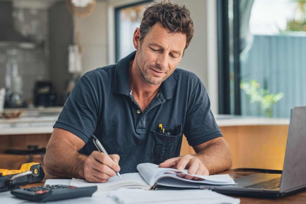 radie business owner reviewing year-end business paperwork with Construction Diary, calculator, and financial documents for tax planning